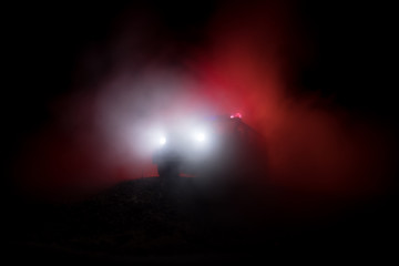 Fototapeta na wymiar Police car chasing a car at night with fog background. 911 Emergency response police car speeding to scene of crime.