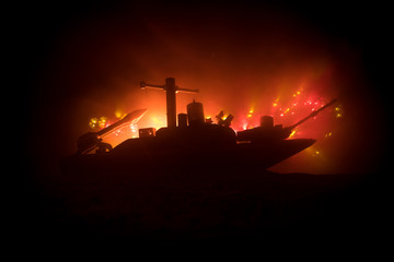 Sea battle scene. Silhouette of military war ship on dark foggy toned sky background. Explosion and...