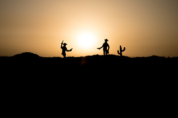 Cowboy concept. Silhouette of Cowboys at sunset time. Cowboys silhouettes on a hill with horses.