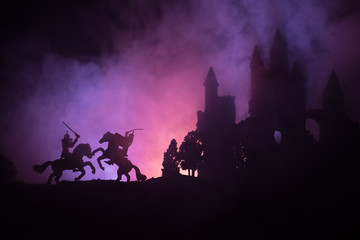 Silhouettes of figures as separate objects, fight between warriors on dark toned foggy background with old gothic castle