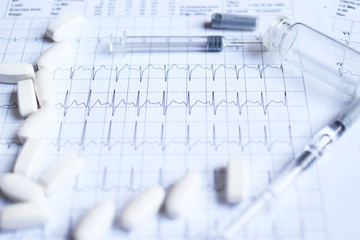 pills and syringes on cardiogram background