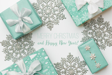 Beautiful christmas gifts and silver snowflakes isolated on white background. Turquoise colored...