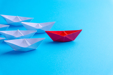 White and red paper ship in one direction on blue background. Business for innovative solution...