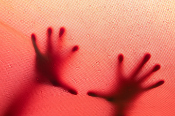 Blurry finger hand silhouette behind on the fabric color pink with water drops,Halloween concept.