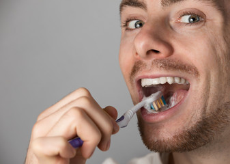 Man brushing his teeth, grey background