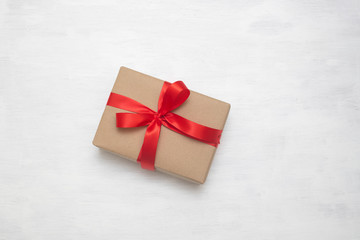 Wrapped vintage brown gift box with red ribbon bow, isolated on white