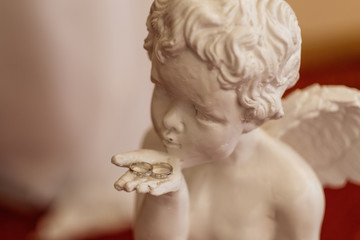 Two wedding rings on the palm of a statue of an angel. Wedding day