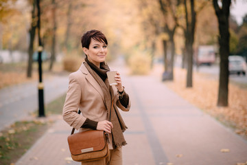 stylish young woman uses smartphone against background of autumn street