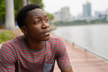 Young handsome African man relaxing and thinking at the park