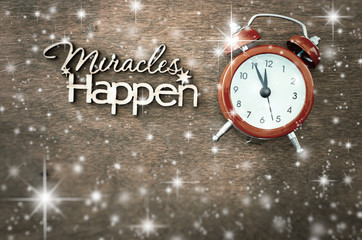 Inscription miracles happen and alarm clock on a wooden background. Concept of inspiration and hope.