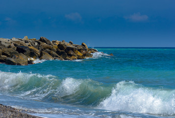 Wellen des türkisen Meeres am Strand mit Wellenbrecher