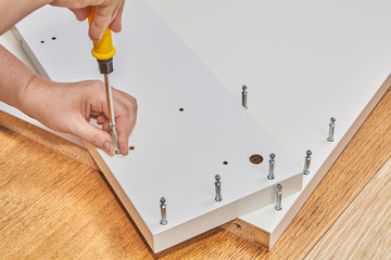 Installer uses cam lock screws as fasteners for flat-pack furniture.