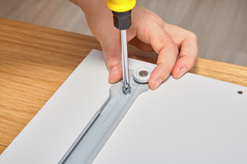 Joiner is mounting slide bracket for drawer using screwdriver.