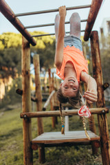 Fototapeta premium Girl hanging upside down on a horizontal ladder in a park