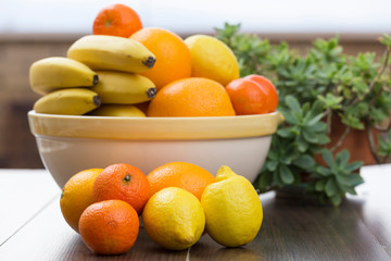 diverse fruits, all citrus, in front of a fruit bowl filled with citrus and bananas