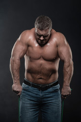 Fototapeta na wymiar muscular man training with a harness on a black background