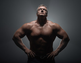Fototapeta premium Powerful muscular bodybuilder posing on a black background. concept of strength and health