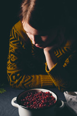 Hipster woman in yellow sweater looking at ripe cranberries harvest on the table