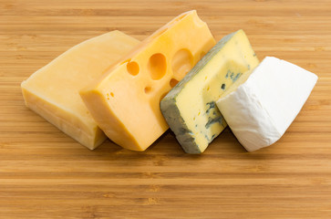 Pieces of various cheese on the bamboo cutting board
