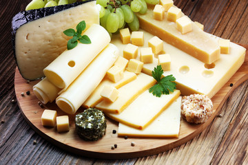 Cheese platter with different cheese and grapes.