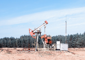 Fototapeta na wymiar Oil production, oil well stands on the field among the forest, blue sky, extraction of petroleum