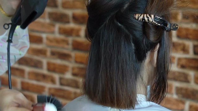 Close up of woman at the hair salon getting a haircut and drying blond hair with hair dryer and round brush. Slow motion 120fps