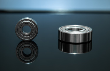 Close up view. Spare part is bearing placed on black glass floor. There is reflection with low light.
