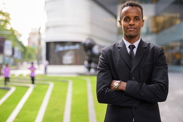 Fototapeta premium Portrait of successful young African businessman outdoors with arms crossed