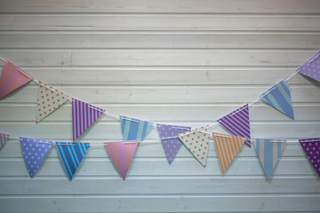 On a white wooden wall garland of colored flags.