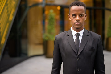Portrait of young African businessman wearing suit outdoors