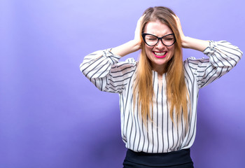 Young woman blocking her ears on a solid background