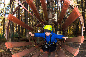 boy in climbing equipment on a children's obstacle course