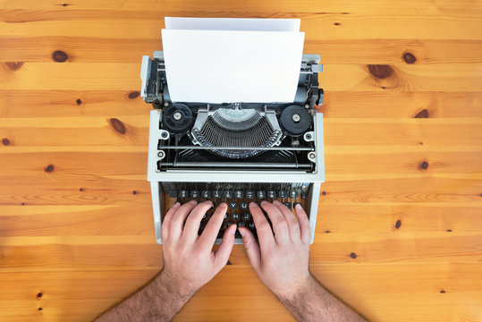 Writer's hands. Old retro typewriter on wooden desk.