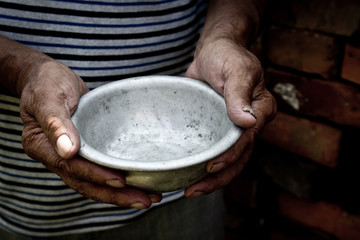 The poor old man's hands hold an empty bowl. The concept of hunger or poverty. Selective focus. Poverty in retirement.Homeless. Alms - obrazy, fototapety, plakaty