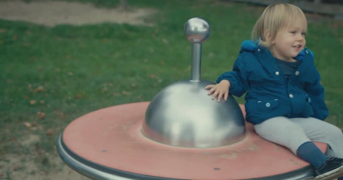 Mother spinning toddler on play equipment