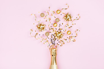Champagne bottle with christmas decoration from confetti stars, golden balls and party streamers on...