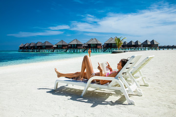 Happy girl riding a book at topical beach on Maldives.