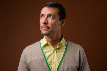 Portrait of handsome man thinking against brown background