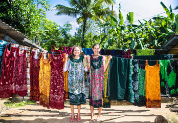 Fototapeta premium Two girls dress up are joking in the factory of batik at Weligama, Sri Lanka.