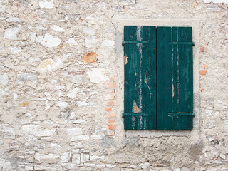 Old weathered green wooden window and damaged stone wall background