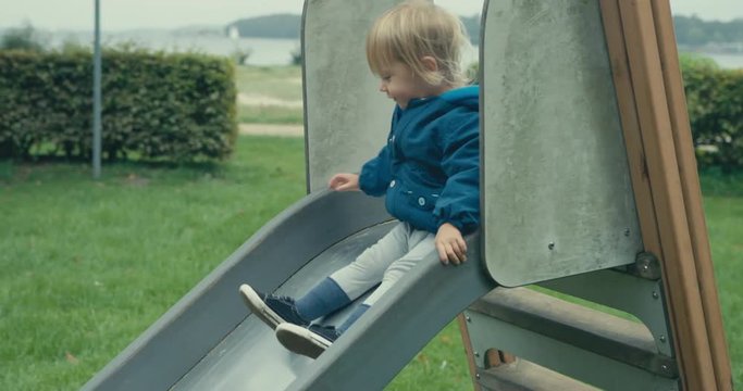 Little toddler going down a slide in the park