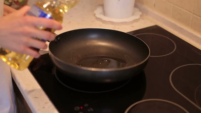 Chef pouring vegetable oil to the pan. Pouring vegetable oil into frying pan. Chef pouring oil into the frying pan for cooking.
