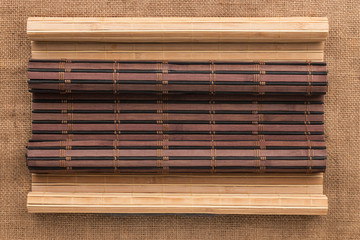 Dark and light bamboo mat in the form of a scroll lie on the burlap.