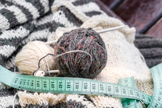 Wool coats, knitting needles, fabric meter and woolen clothes. close-up