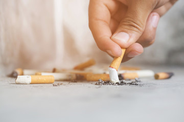 Hand putting out a cigarette,cigarette butt on Concrete floor, bare cement.	smoking a cigarette....