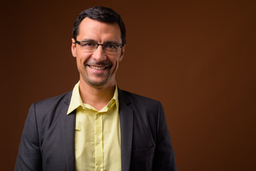 Portrait of handsome businessman smiling against brown background