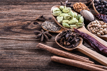 Different types of whole Indian spices in wooden background close-up.