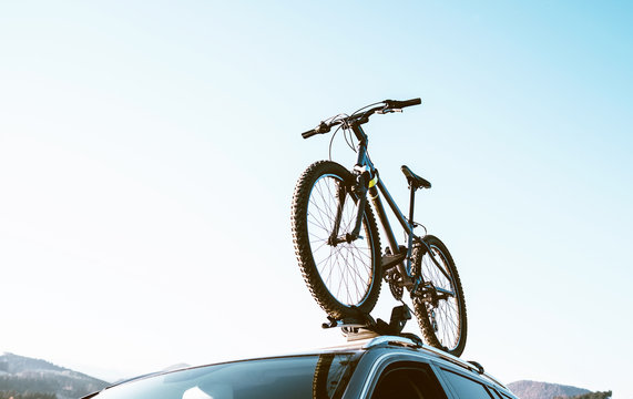 Mountain Bicycle fixed with Roof Mounted Bike Carriers instaled on white Auto roof travel concept image