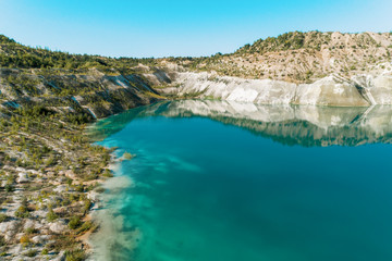 An old gypsum quarry filled with blue and pure water. Aerial view, from top to bottom