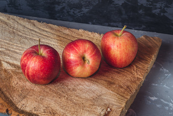 Three red apples on a wooden saw